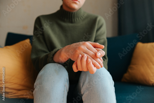 Quadro su tela A person sits on a couch, resting their hands together while appearing thoughtful