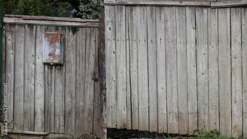 Old vintage rustic fence with gate and rusty textured iron mailbox as gray rural fence texture with metal oxidized mail box
