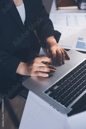 Auditors collaborating in modern office, analyzing financial documents and using calculator with a laptop displaying charts. Audit and taxes in business