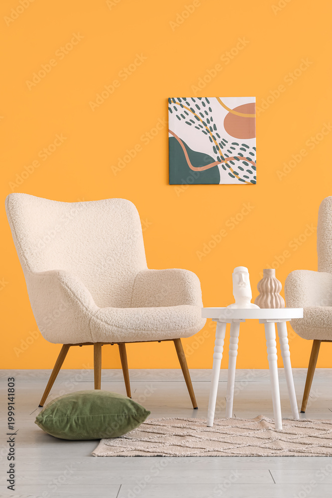 Fototapeta premium Comfortable armchair and coffee table near orange wall in interior of living room