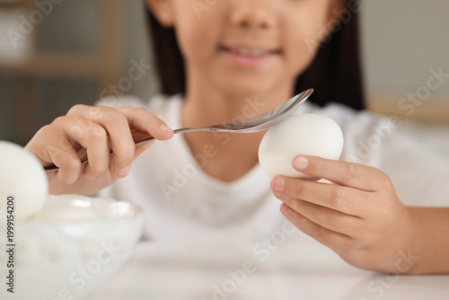 Cute girl breaking boiled e...