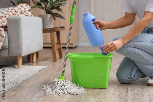 Woman with mop pouring dete...