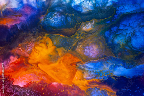 Colorful abstract art created with paint on a surface, showing deep blue and bright orange blending in unique shapes, captured in a studio setting