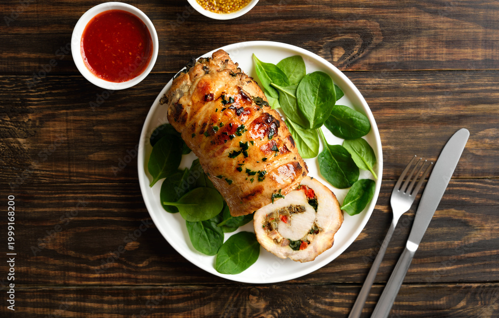 Fototapeta premium Delicious roasted pork roll stuffed with mushroooms, onion, red bell pepper, spinach