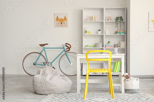 Interior of room with children's workplace, shelving units, bicycle and beanb...