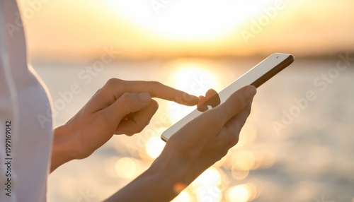 Woman using smartphone at sunset by the waters edge.