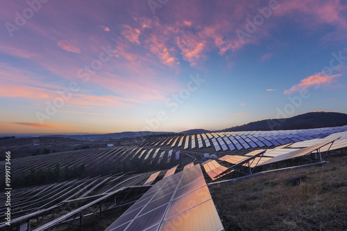 Aerial View of Solar Farm on Rolling Hills at Sunrise