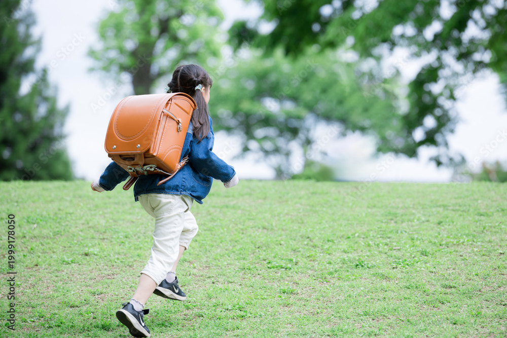 Fototapeta premium ランドセルで走る元気な小学生の全身ポートレート小学生低学年の登校や下校などの通学や成長ののイメージ 顔無しの後ろ姿