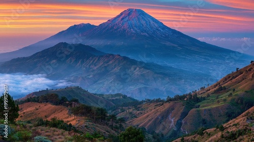 Colorful sunrise landscape with majestic mountain peak above misty valleys and rolling hills, scenic nature background with copy space for travel or advertising.
