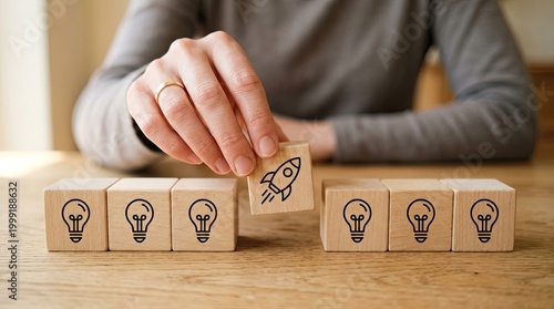 Hand placing a rocket icon block among lightbulb ideas on a wooden table for innovation
