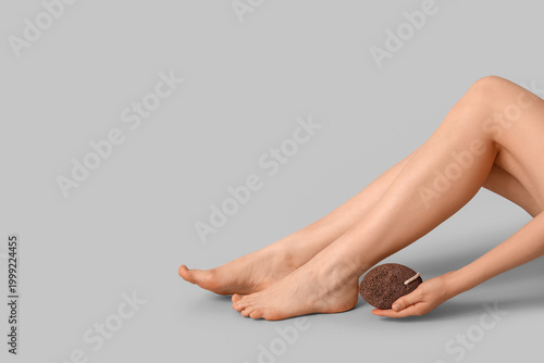 фотографія Legs of pretty young woman with pumice on grey background