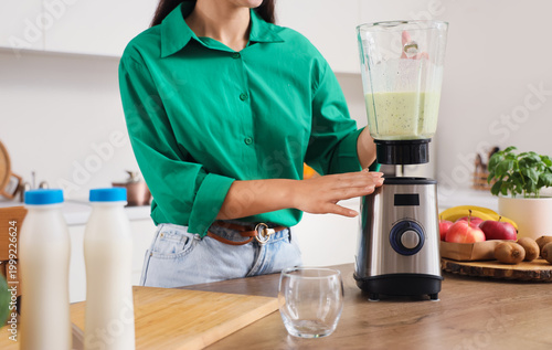 Young woman making smoothie...