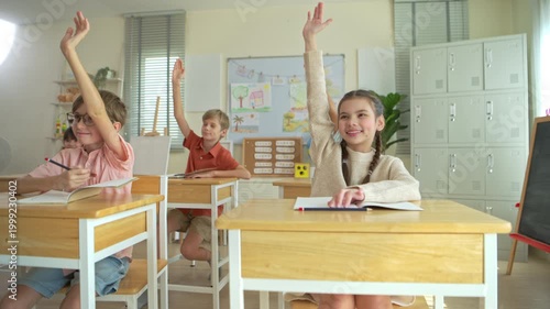 Group of students raising hands eagerly in classroom, representing active participation and engaging learning environment