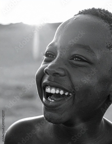 close up image of a young black boy laughing as sunlight hits his face,  soft golden  