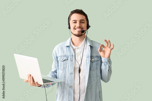 Foto Male technical support agent with laptop showing OK on mint background