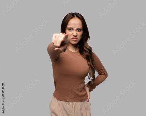 Confident young woman pointing at camera isolated on neutral background