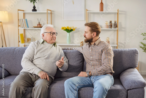 Foto Serious senior father sitting on sofa and having meaningful conversation with his adult son