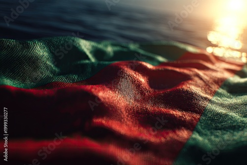 Rippling fabric with red and green stripes, lit by golden sun on water