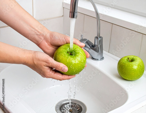 Washing green apple in kitchen sink
