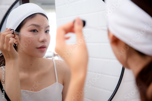 Beautiful young asian woman applying serum for rejuvenation on facial looking mirror, beauty woman applying collagen for treatment skin, self-care, skincare and makeup, cosmetic and makeup.