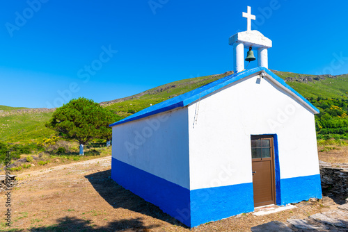 Greek orthodox church small chapel in Perdiki mountain village on Ikaria island, Greece longevity blue zone by garden tree