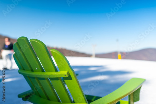 Wintergreen Resort Virginia with wooden chaise lounge reclining chair by scenic view of Blue Ridge mountain ski slope with people skiing in winter