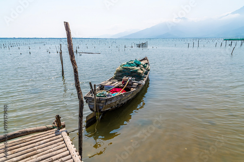 фотографія A view of a boat moored to a jetty used to access an oyster farm on the Lap An L