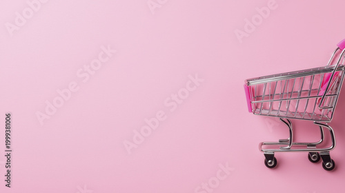 Miniature shopping cart on pastel pink background, symbolizing retail and consumerism, evokes playful shopping experience