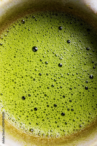 Close-up of bubbles forming whisked matcha foam during traditional Japanese green tea preparation.