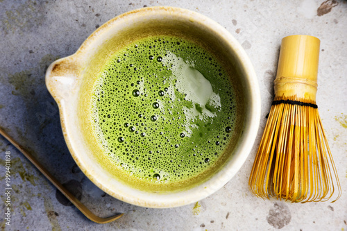 Matcha tea with fine foam texture served in a bowl, paired with bamboo whisk.