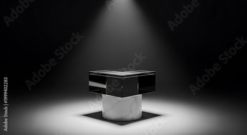 A black and white image of a cube shaped object on a pedestal lit by a spotlight in a dark room