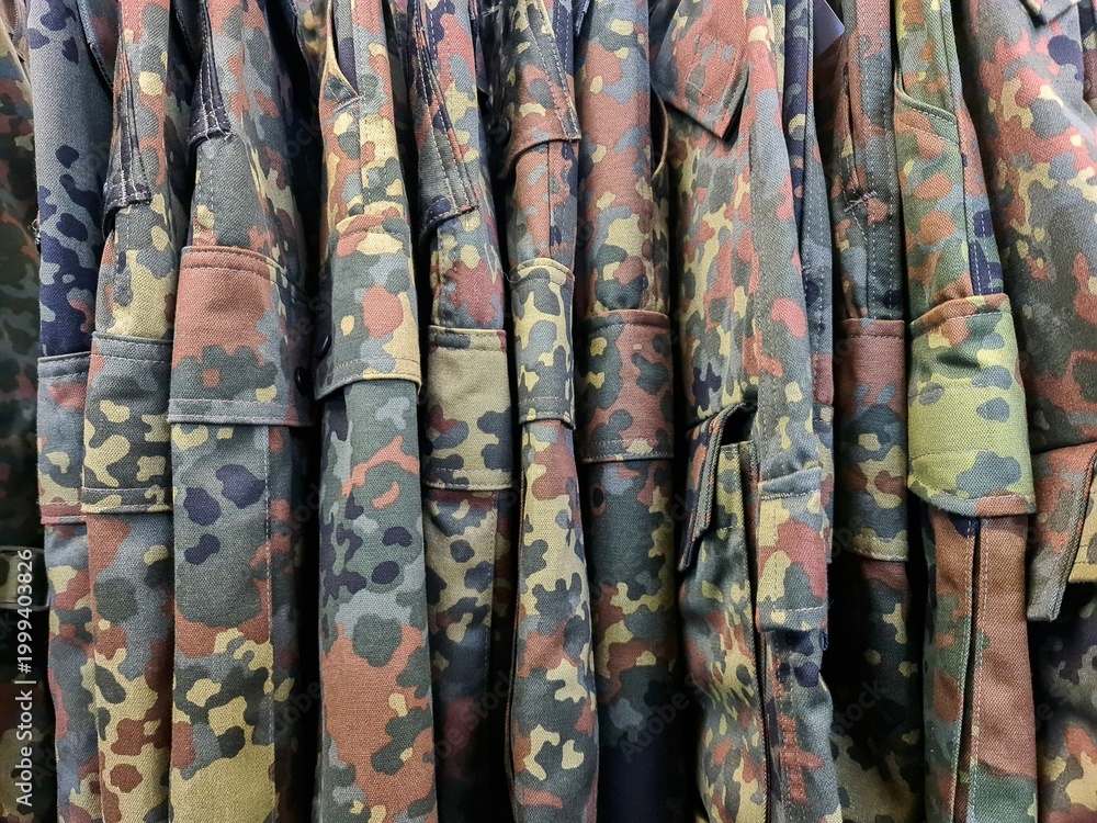 Obraz premium Military camouflage uniforms hanging on a rack