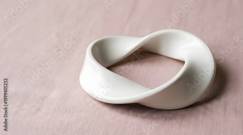 Matte White Ceramic Infinite Loop Mobius Strip Resting on Dusty Rose Linen Background for Sustainability Concept