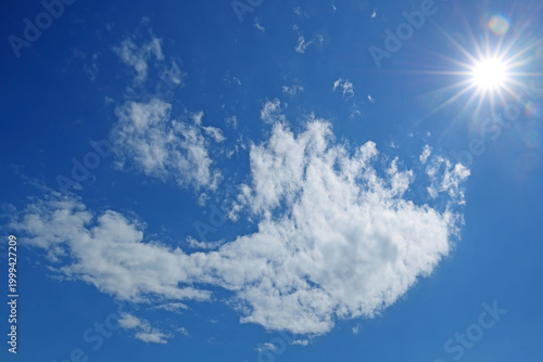 Slika na platnu bright sun on blue summer sky with moving fluffy clouds, sun shining sunbeams, white cumulus clouds on sunshine day
