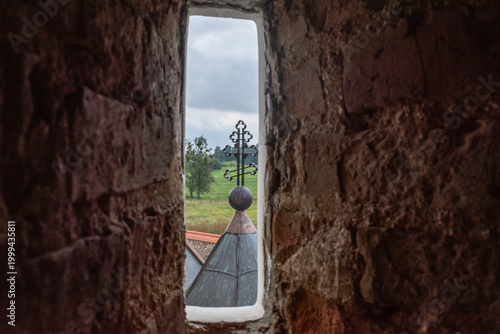 фотографія View of a church cross through a narrow stone window embrasure