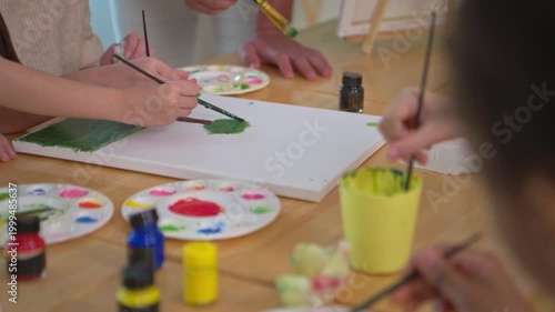 Focused student painting a tree on canvas in classroom art activity, representing creativity and concentration