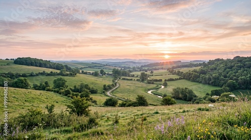 Sunset over rolling hills with trees and winding road in countryside landscape