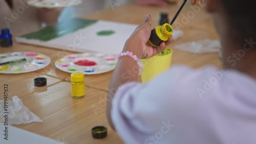 Focused student painting a tree on canvas in classroom art activity, representing creativity and concentration