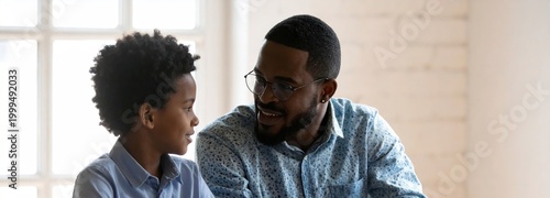 Happy African American father talking to son at home. family bonding, black fatherhood, father and son, parenting.