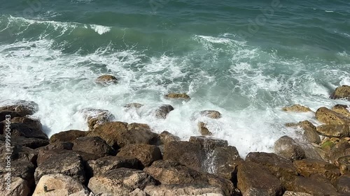 a wave crashes against rocks along the Mediterranean shoreline near Haifa, Israel