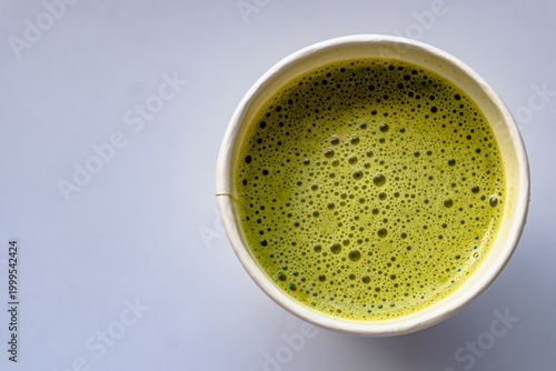 Close Up of Paper Glass Hot Matcha or Green Tea take-away, Top Angle View. Wooden table and place for Text and Graphic Resources.