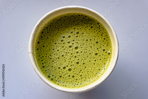 Close Up of Paper Glass Hot Matcha or Green Tea take-away, Top Angle View. Wooden table and place for Text and Graphic Resources.