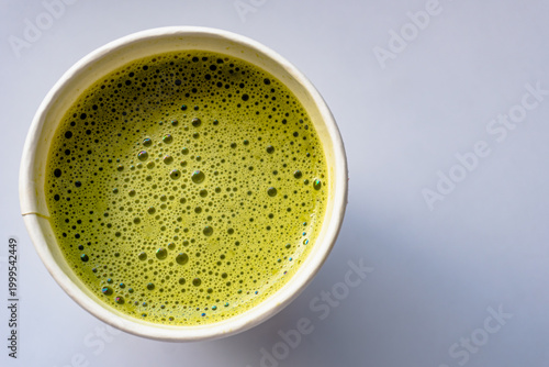 Close Up of Paper Glass Hot Matcha or Green Tea take-away, Top Angle View. Wooden table and place for Text and Graphic Resources.