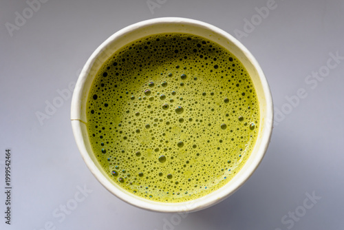 Close Up of Paper Glass Hot Matcha or Green Tea take-away, Top Angle View. Wooden table and place for Text and Graphic Resources.