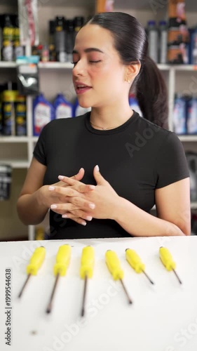 Young female hardware store employee presenting a set of screwdrivers while talking to the camera