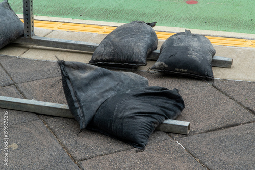Canvas-taulu Heavy duty black sandbags stabilize metal frames on concrete pavers, with a yell