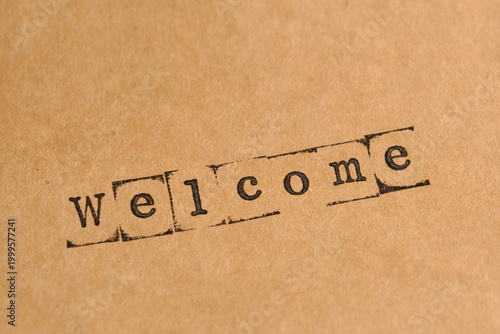 Welcome word stamped at an angle on weathered paper, showing high detail of ink and grain.