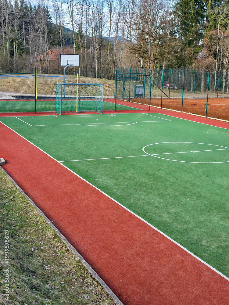 Fototapeta premium Empty multi-sport playground with artificial turf and basketball hoop in the park.