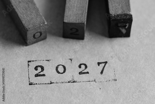 Black and white macro wooden stamps. 2027 is clearly printed on textured surface.