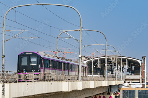 Close up image of Fresh, new rake of Pune metro train exits metro station and runs on overhead track .